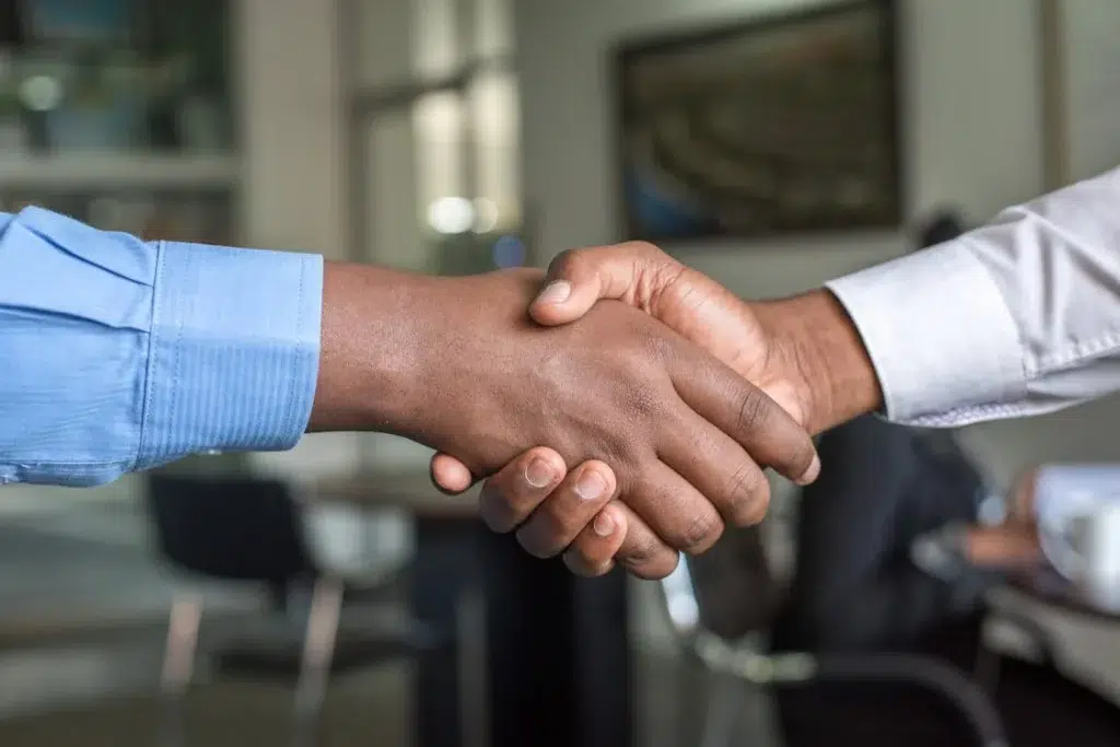 A salesperson and client shake hands after concluding a deal