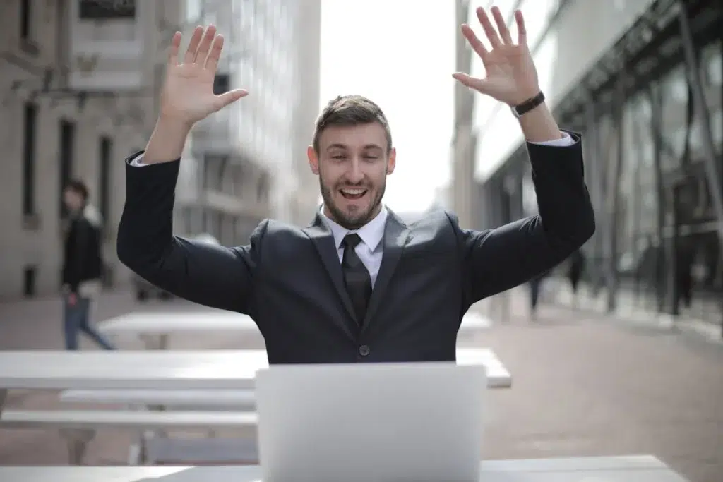 A businessperson raises his hands to celebrate success