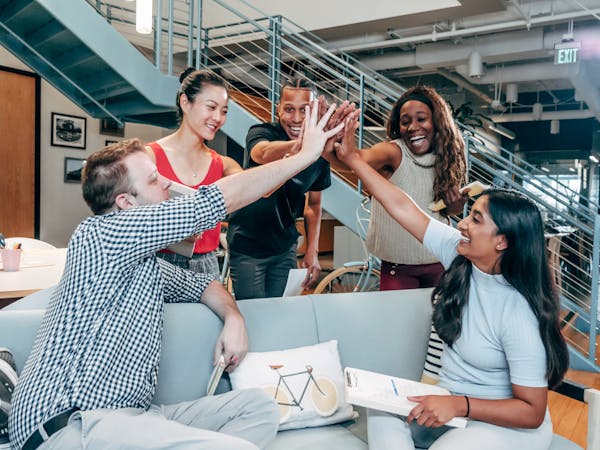 An outsourced SDR team exchanges high fives to celebrate results