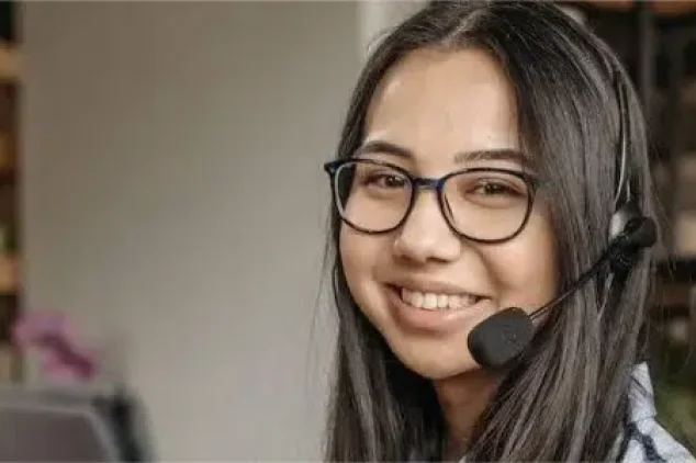 A woman at a desk wearing a headset, engaged in cold calling.